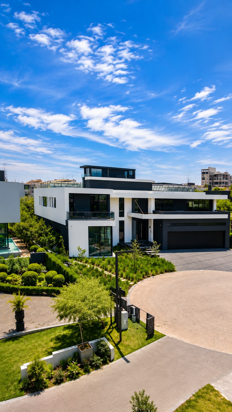 Modern white and charcoal residence with landscaped garden, paved circular driveway and blue sky — a Ramusia Engineering & Projects build