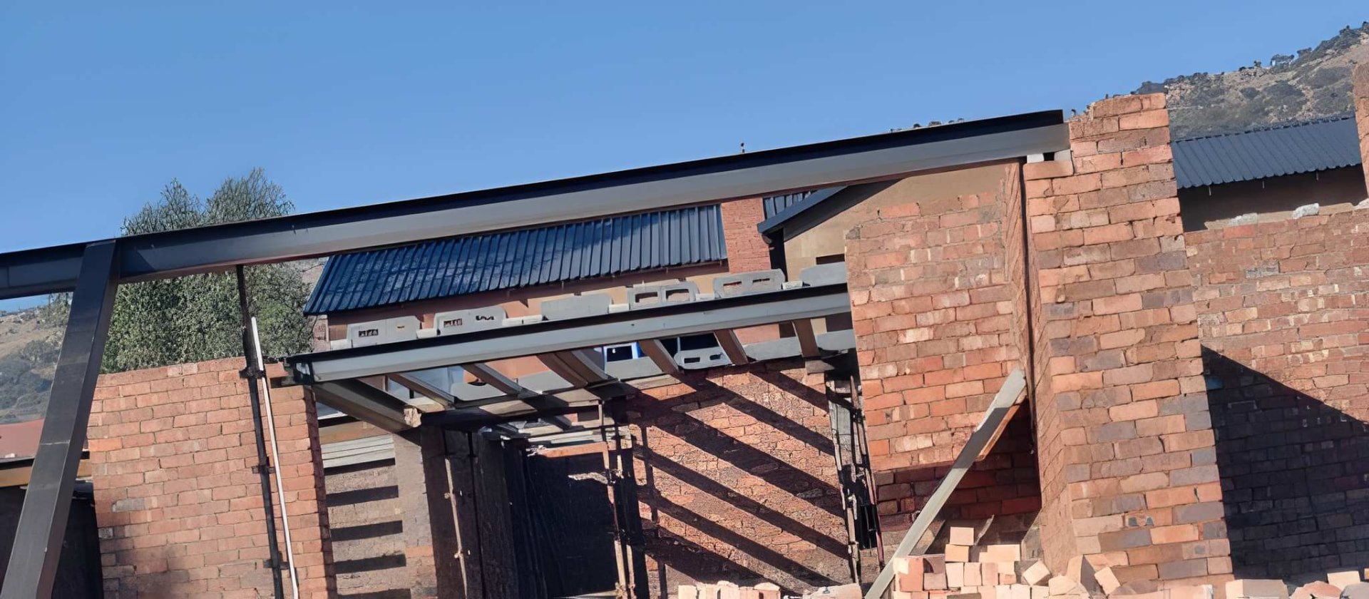 Steel roof structure installed over face-brick walls on a Ramusia project site